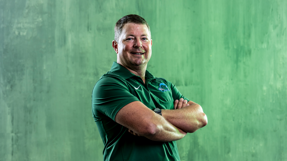 Will Hall posing in a Tulane green shirt with a green background