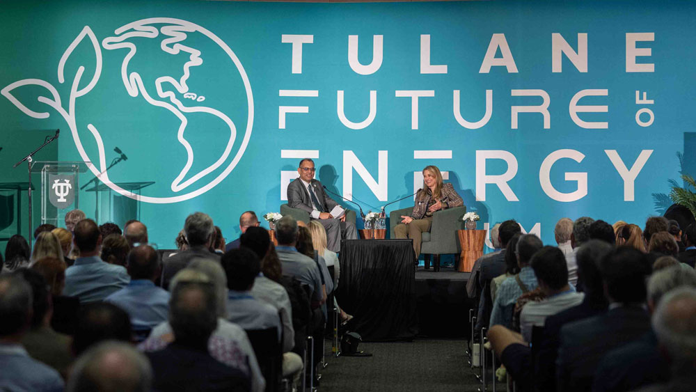 Two speakers on stage at the Tulane Future of Energy conference, addressing an audience.