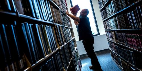 Person pulling book from library shelf.