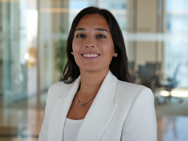 Smiling woman in white blazer against a modern office background.